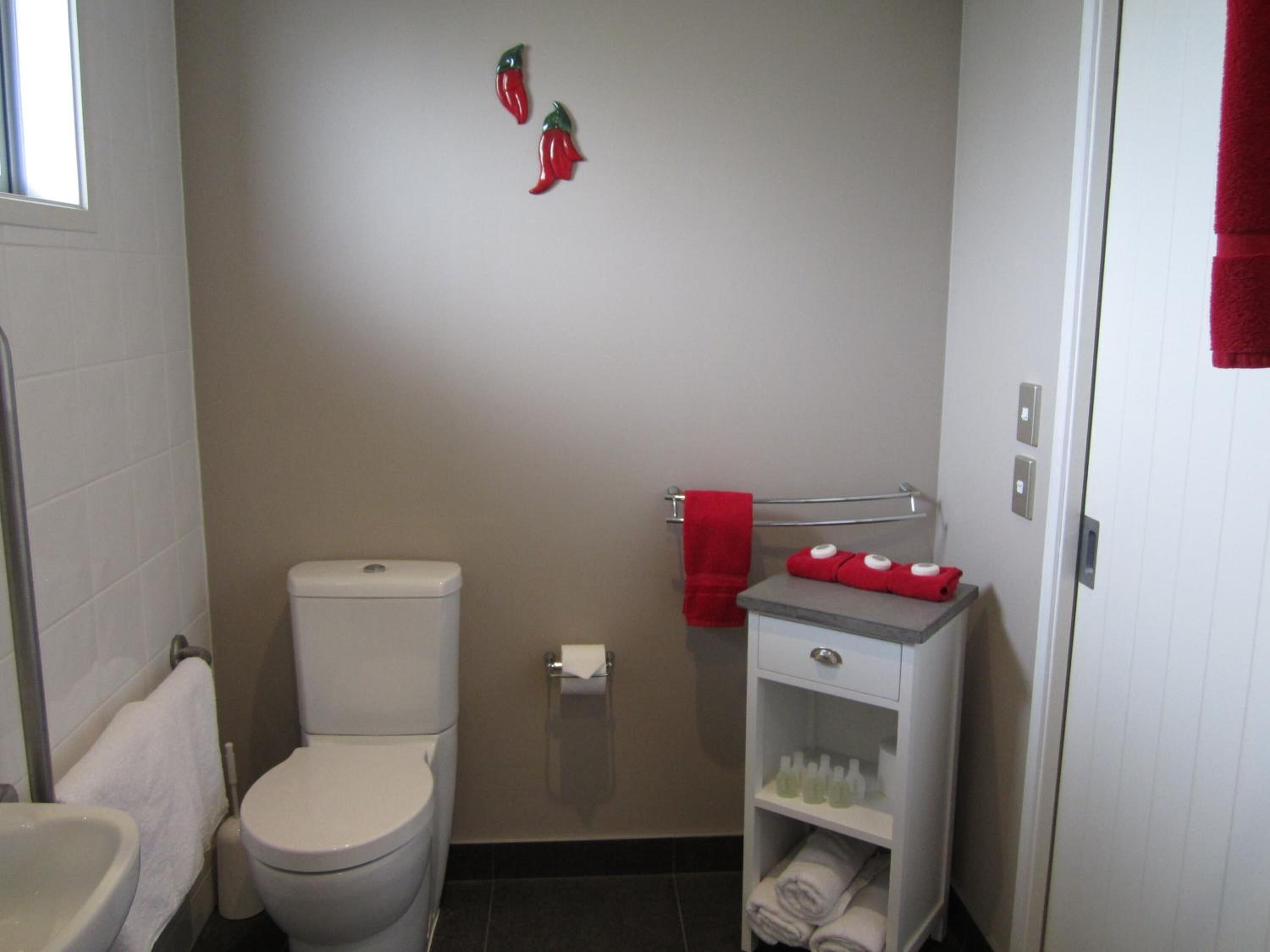 Une petite salle de bain comprenant des toilettes, un lavabo, un porte-serviettes et une étagère avec des articles de toilette.