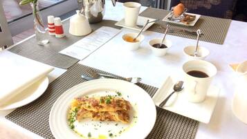 A breakfast setting with a plate of food, coffee cups, a teapot, and condiments on a table.