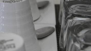 Una fila de vasos de plástico blancos y un recipiente de vidrio sobre una mesa.