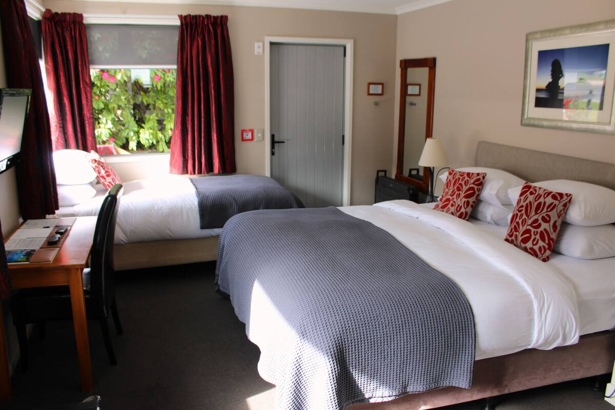 Habitación de hotel con dos camas, un escritorio y una silla.