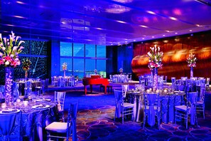A banquet hall with round tables, chairs, and floral centerpieces.