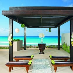 Relax in a serene oceanfront seating area with a pergola, two benches, and lush greenery.