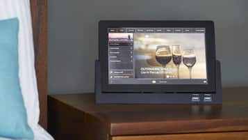 Une tablette affichant un menu, posée sur une table de chevet en bois.
