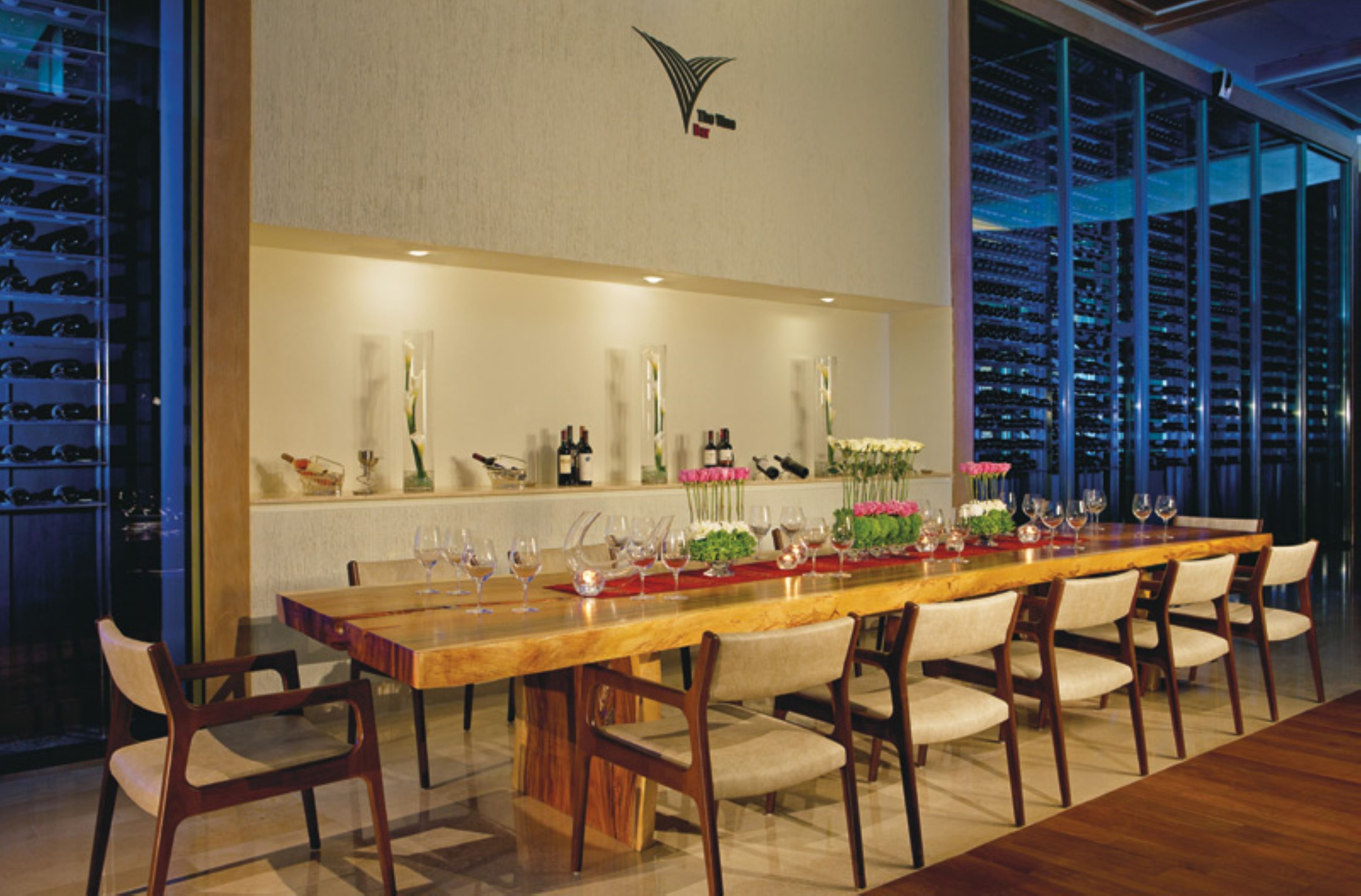 A long dining table with chairs, a wine rack, and decorative items.