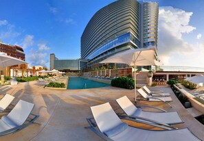 A modern hotel with a curved building, a pool area with sun loungers, and a bar/lounge area. - Secrets The Vine Cancun - Adults Only - All Inclusive (Cancun)