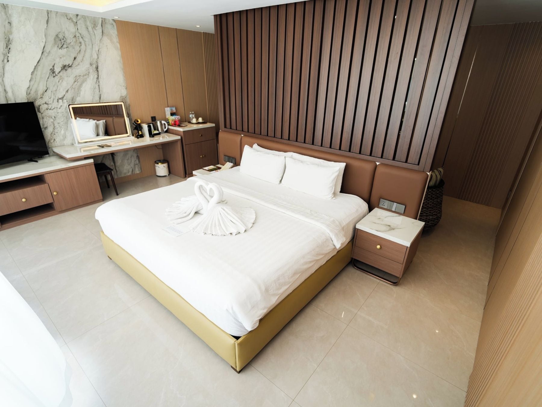 Ein modernes Hotelzimmer mit einem großen Bett, einem Schreibtisch, einem Fernseher und einem Kleiderschrank.