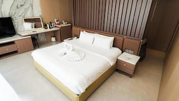 Ein modernes Hotelzimmer mit einem großen Bett, einem Schreibtisch, einem Fernseher und einem Kleiderschrank.