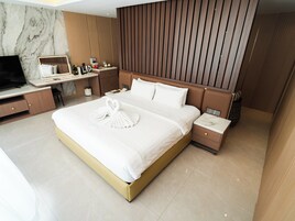 Una habitación de hotel moderna con una cama grande, un escritorio, un televisor y un armario.