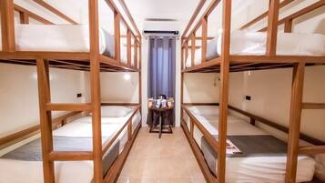 A room with bunk beds, a small table with items, and a curtain.
