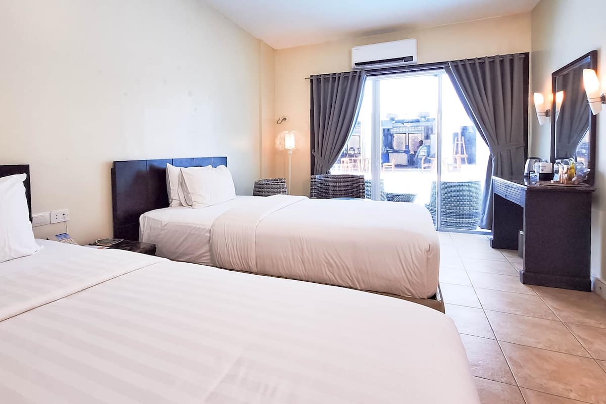 Ein Hotelzimmer mit zwei Betten, einem Schreibtisch und Blick nach außen.