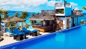 A rooftop infinity pool with a view of the ocean, lounge chairs, and a bar area. - Boracay Ocean Club Resort and Spa (Boracay Island)