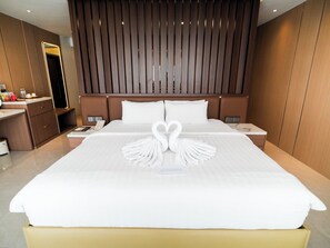 Una habitación de hotel con una cama grande, una mesita de noche, un espejo y un cabecero de madera.
