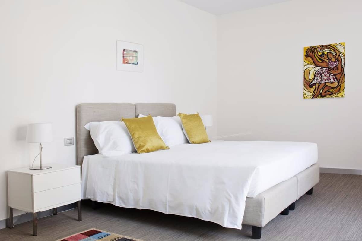 A bedroom with a bed, nightstand, and wall art.