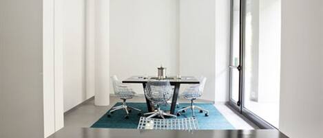 A conference room with a dark wooden table, four office chairs, and a blue carpet.