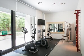A modern gym with cardio equipment, weight machines, and a large mirror. - Zambala Luxury Apartments  (Milan)