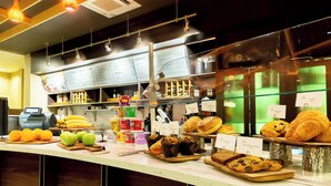 Un comptoir de boulangerie où sont exposés divers produits de boulangerie, notamment des croissants et des muffins, ainsi qu’un assortiment de fruits frais, comme des pommes et des oranges.