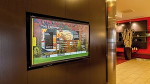 Un écran numérique affichant les plats et les boissons proposés dans le hall d’un hôtel.