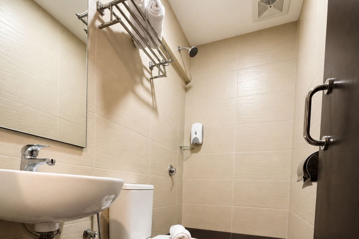 A modern bathroom with a white sink, toilet, and shower.