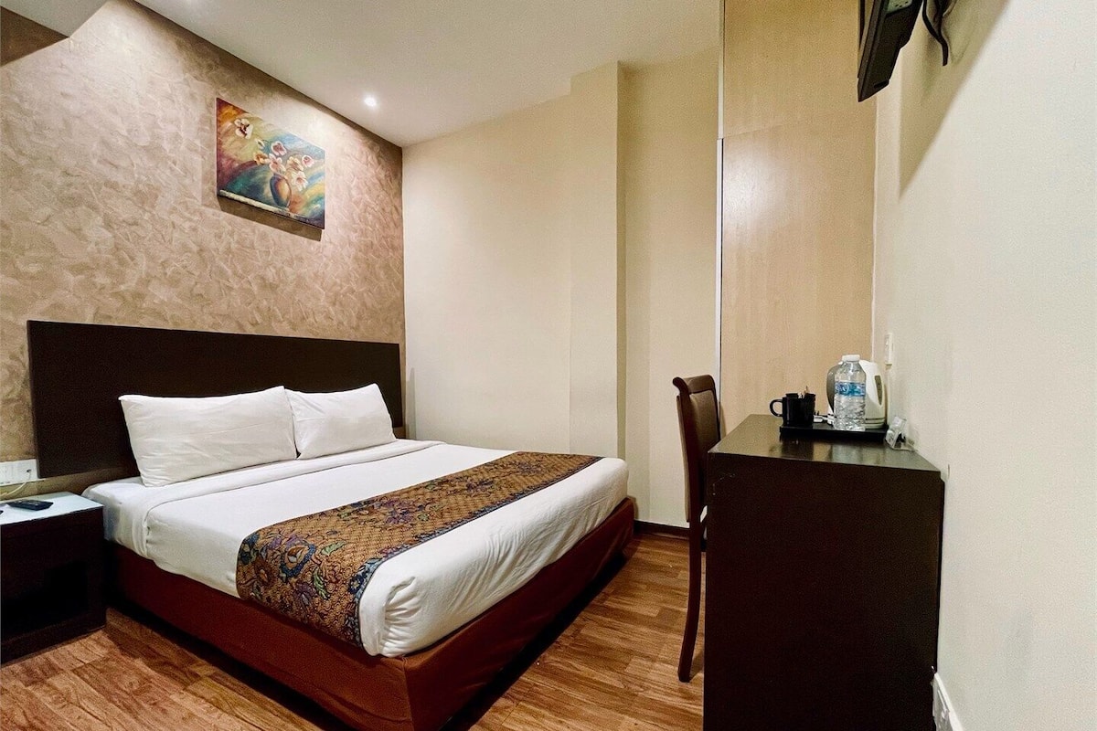 A hotel room with a bed, a desk, and a chair.
