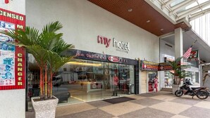 Ein Hotel mit Eingangsbereich, einer Rezeption, Palmen und einem nahegelegenen 7-Eleven-Geschäft.