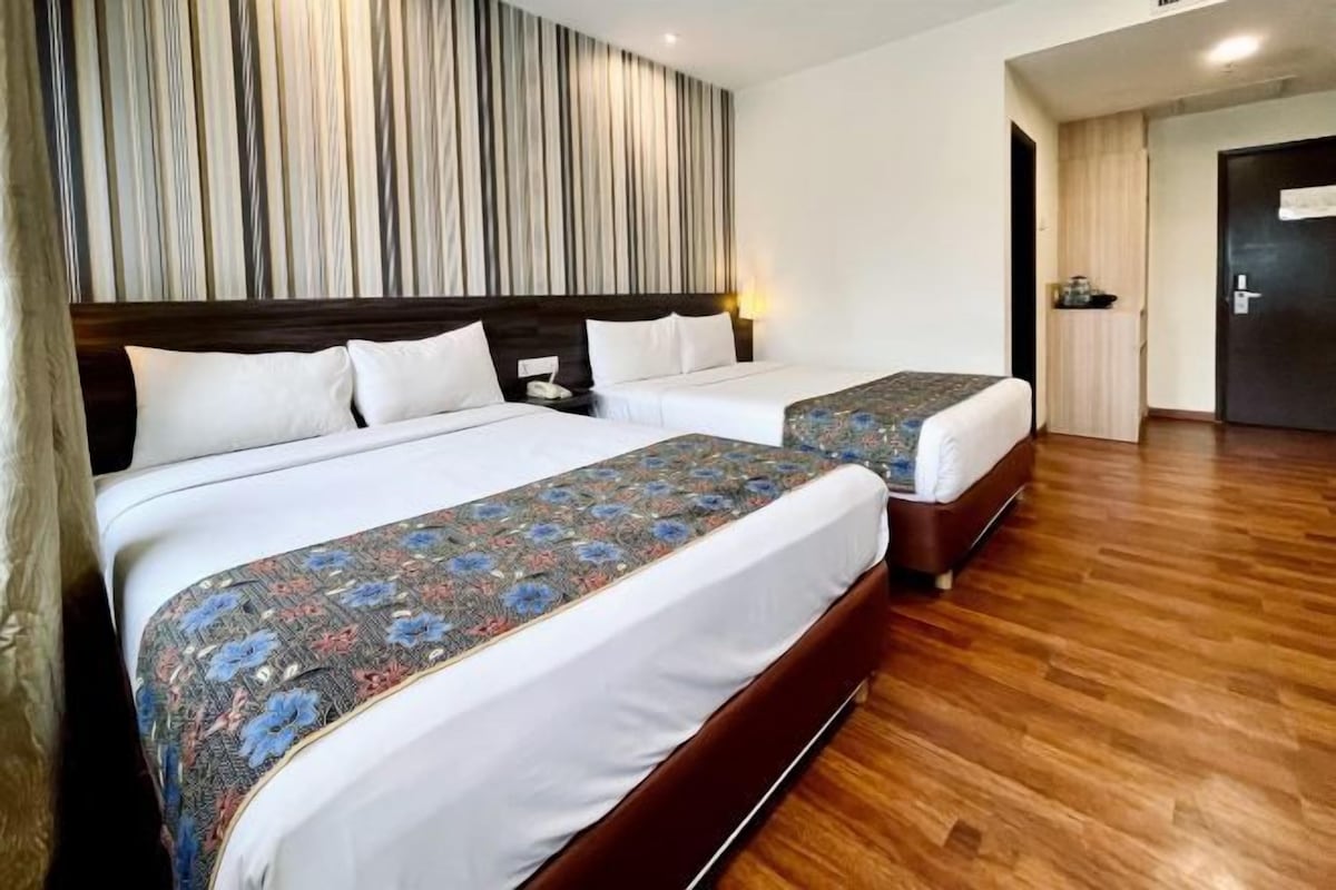 Ett hotellrum med två sängar, trägolv och en randig vägg.