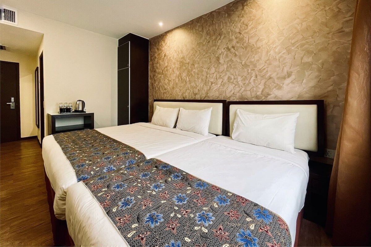 A hotel room with a large bed, a nightstand, a wardrobe, and a textured wall.