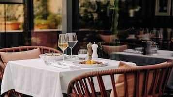 A dining table set with plates, glasses, and cutlery, surrounded by wicker chairs.