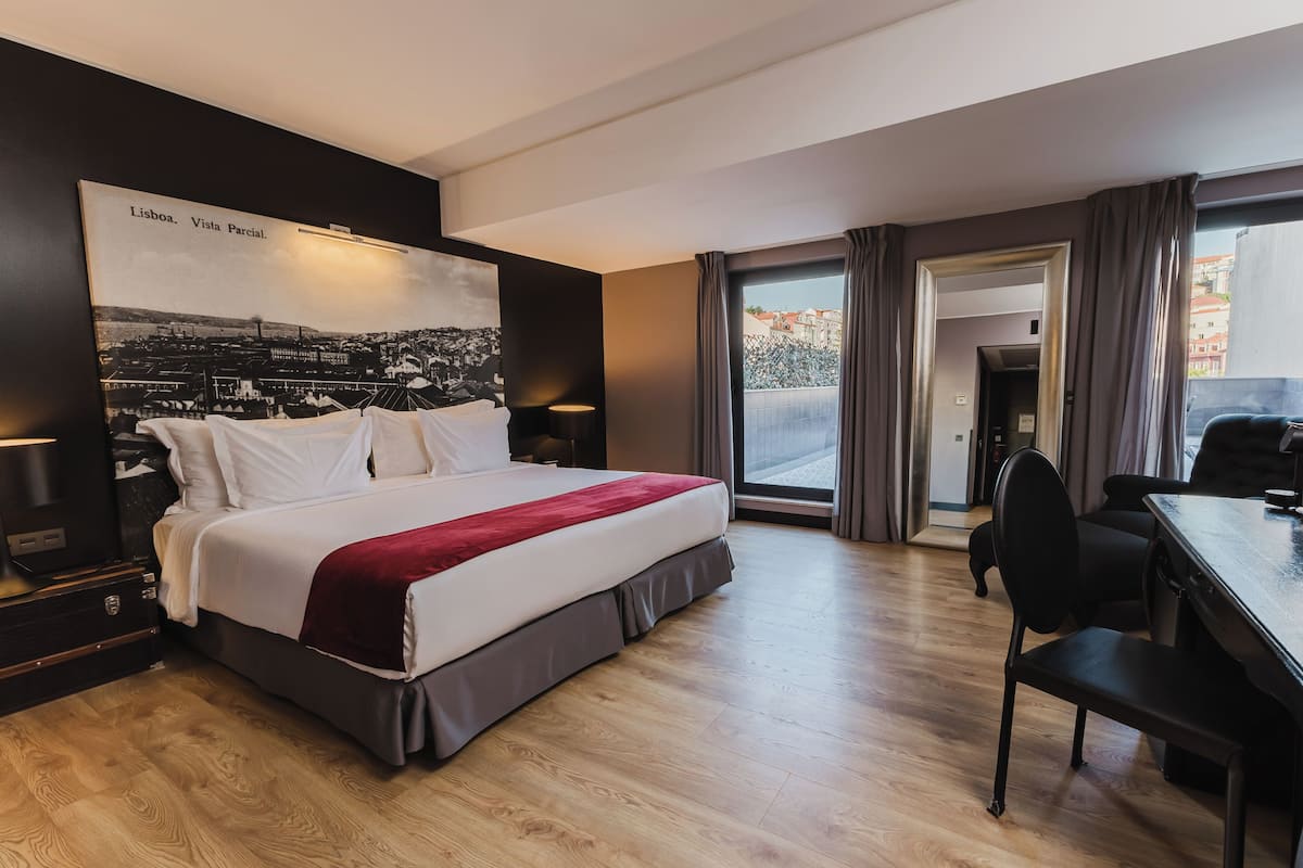 Ein modernes Hotelzimmer mit einem großen Bett, einem Schreibtisch und Blick auf die Stadt.