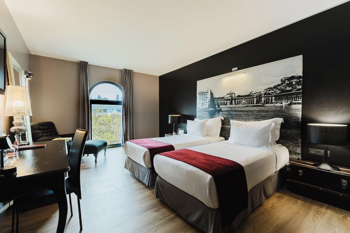 Ein Hotelzimmer mit zwei Betten, einem Schreibtisch und einer Essecke.