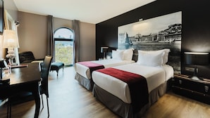 A hotel room with two beds, a desk, and a dining area.
