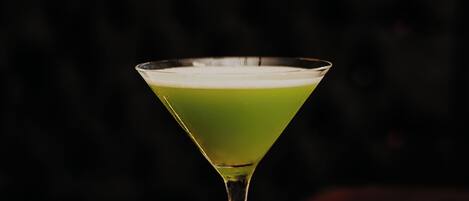 A martini glass with a green liquid on a wooden surface.