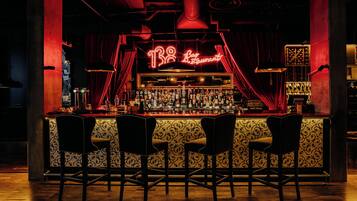Un espace bar agrémenté d'un panneau néon, d'un comptoir et de quatre tabourets de bar.