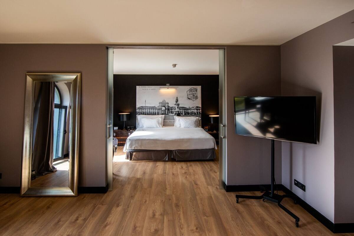 Ein Hotelzimmer mit einem großen Bett, einem Fernseher und einem Spiegel.