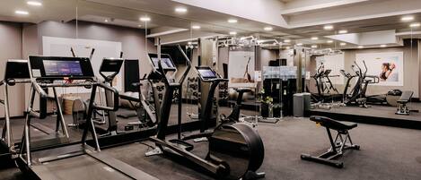 Ein modernes Fitnessstudio mit Laufbändern, Crosstrainern und Rudergeräten.