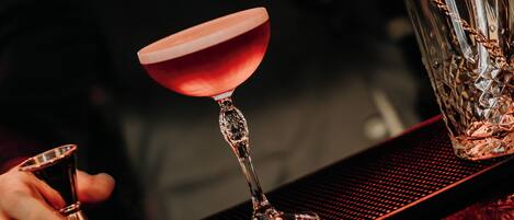 A bar setting with a martini glass, a cocktail shaker, and a bar spoon.