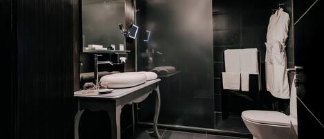 Een moderne badkamer met een donker houten wastafelmeubel, een douchecabine van glas en een wit toilet.