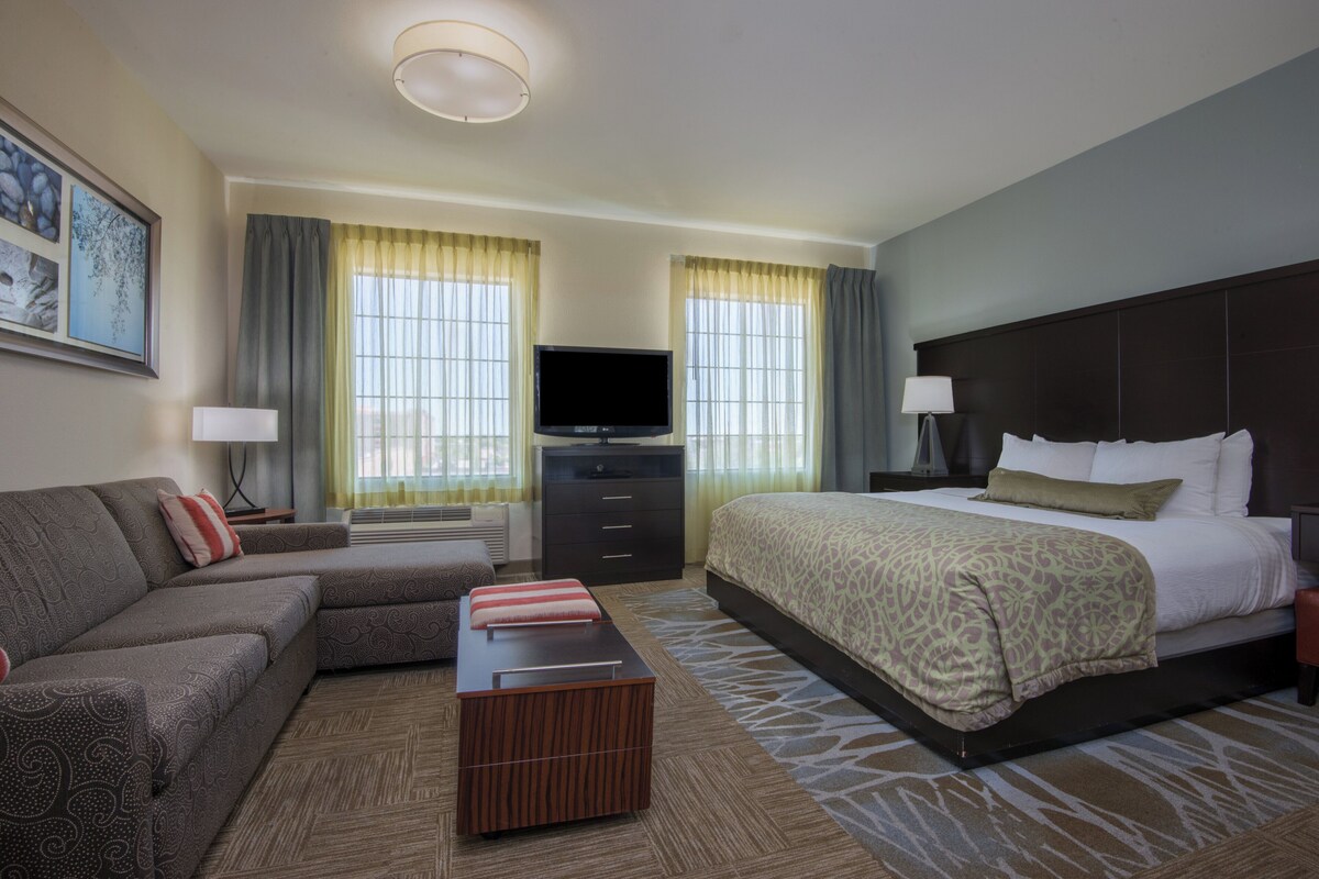 Una habitación de hotel con cama, sofá, televisión y escritorio.