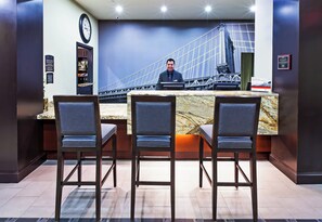 A reception desk with a view of a bridge, three bar stools, a clock, and a signboard. - Staybridge Suites Amarillo - Western Crossing by IHG (Amarillo)