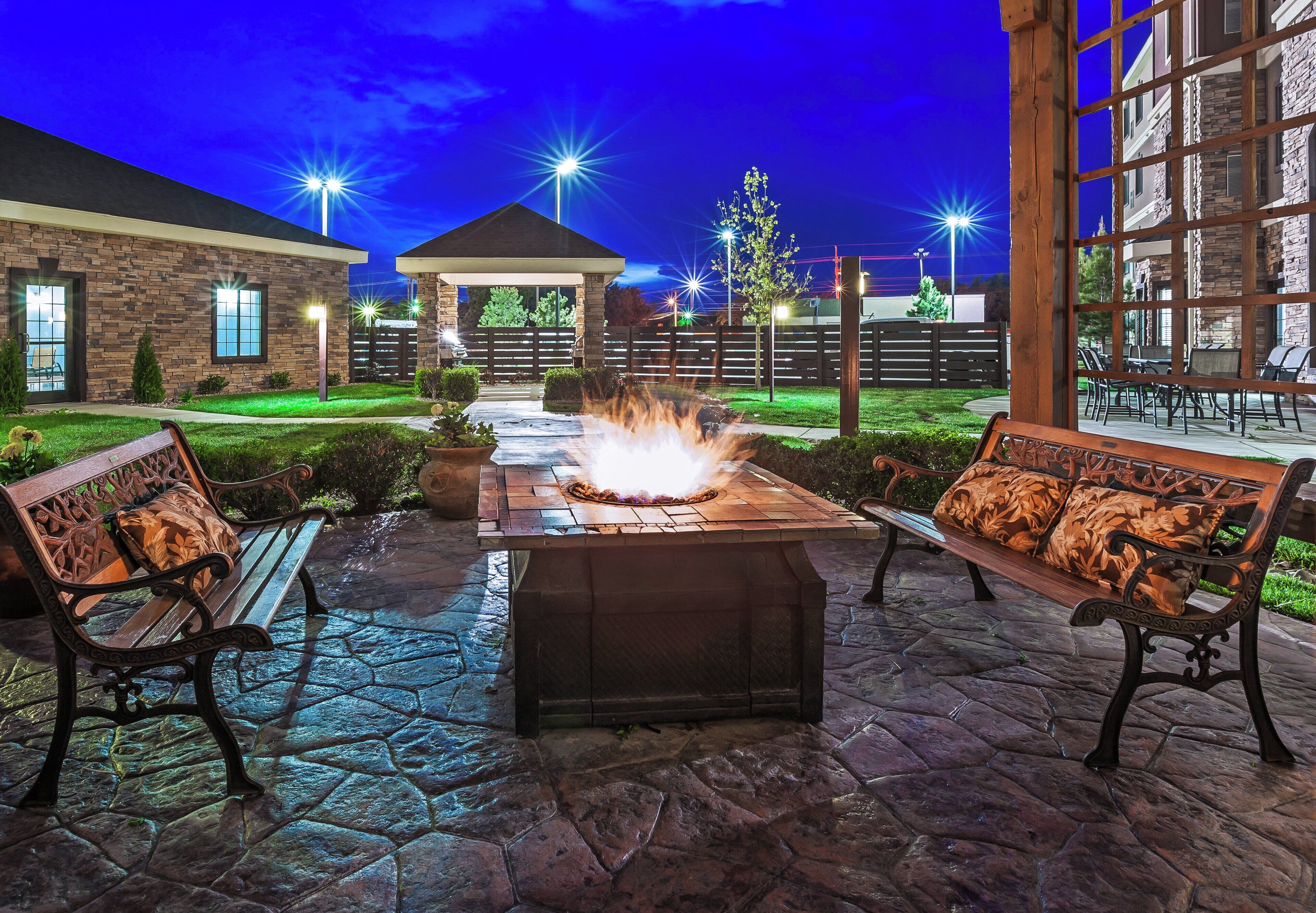 Un patio al aire libre con una chimenea, bancos y un sendero de piedra.