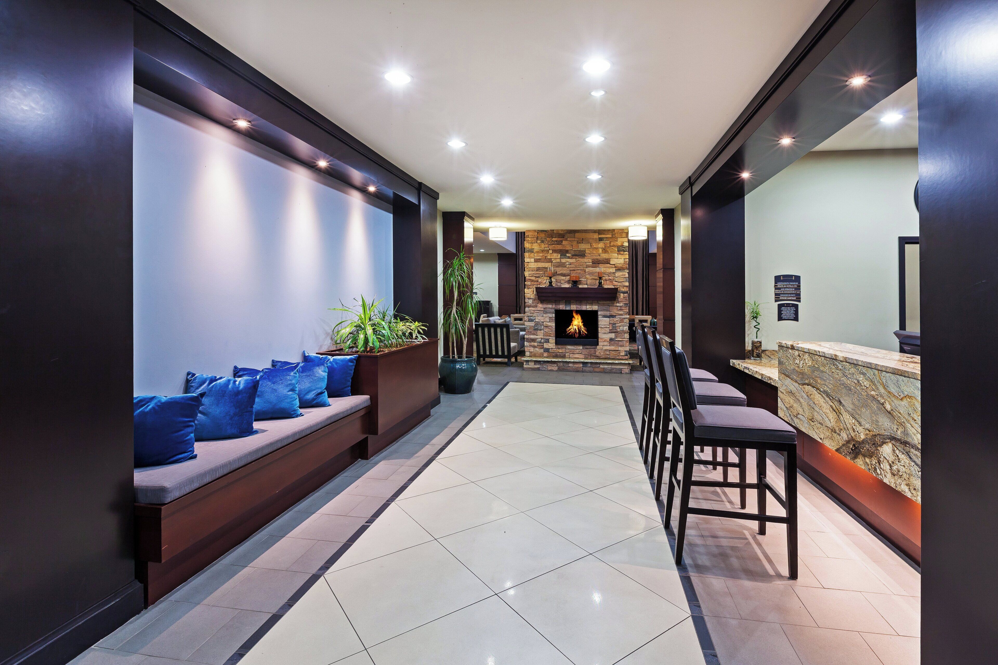 Un hall moderno con zona de estar, chimenea y mostrador de recepción.