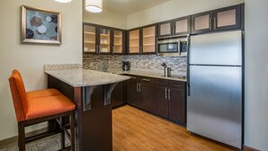 Una cocina moderna con armarios oscuros, electrodomésticos de acero inoxidable y una encimera de granito.