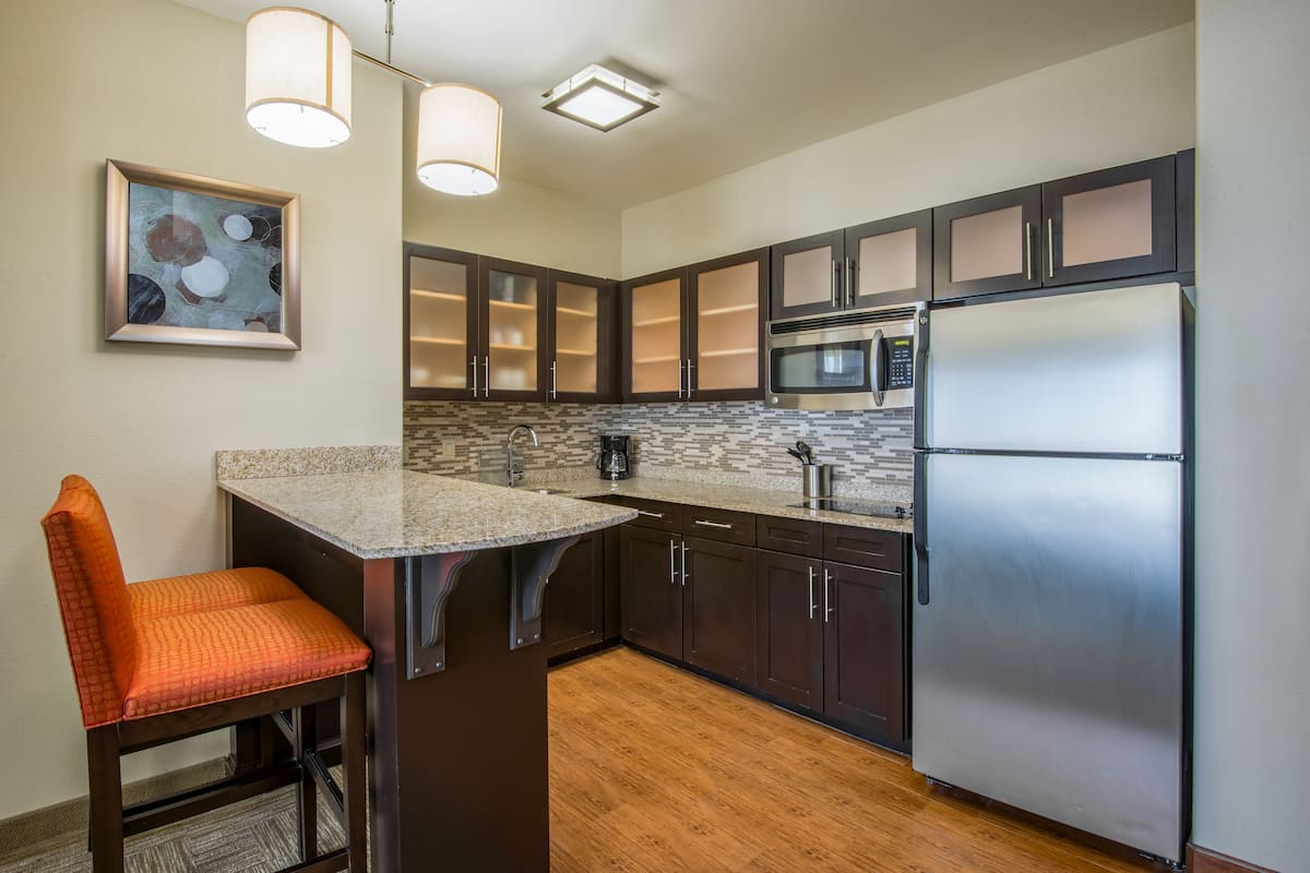 A modern kitchen with dark cabinets, stainless steel appliances, and a granite countertop.