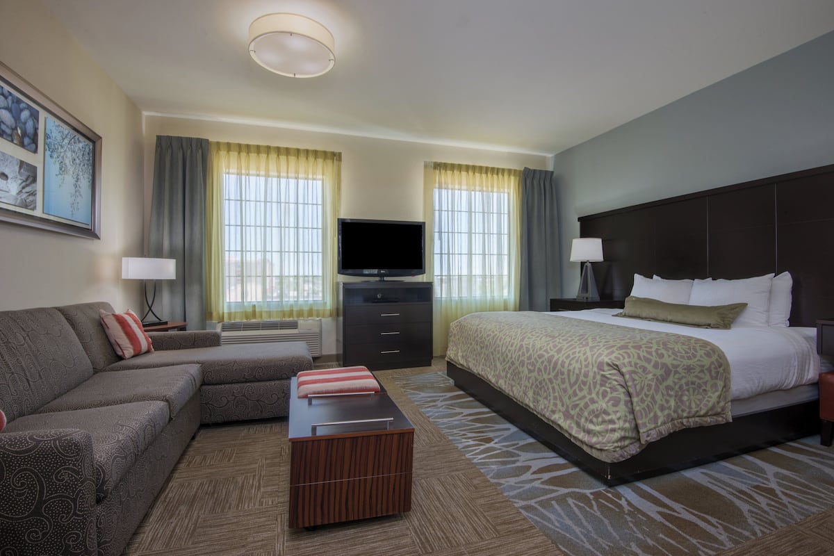 A hotel room with a bed, a sofa, a TV, and a desk.
