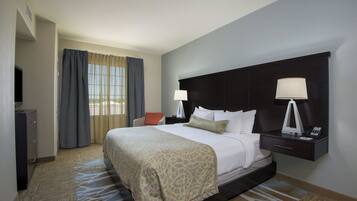 Quarto de hotel com uma cama grande, duas luminárias de cabeceira, uma escrivaninha com telefone e uma cadeira.