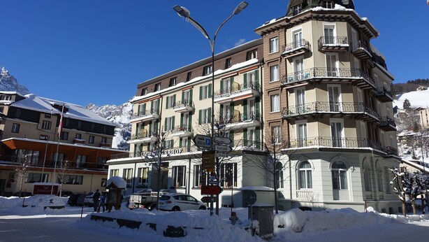 A multi-story hotel with balconies, a snow-covered street, and a clear blue sky. - Hotel Schweizerhof Engelberg (Engelberg)