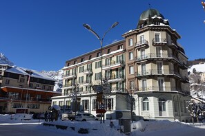 A multi-story hotel with balconies, a snow-covered street, and a clear blue sky. - Hotel Schweizerhof Engelberg (Engelberg)