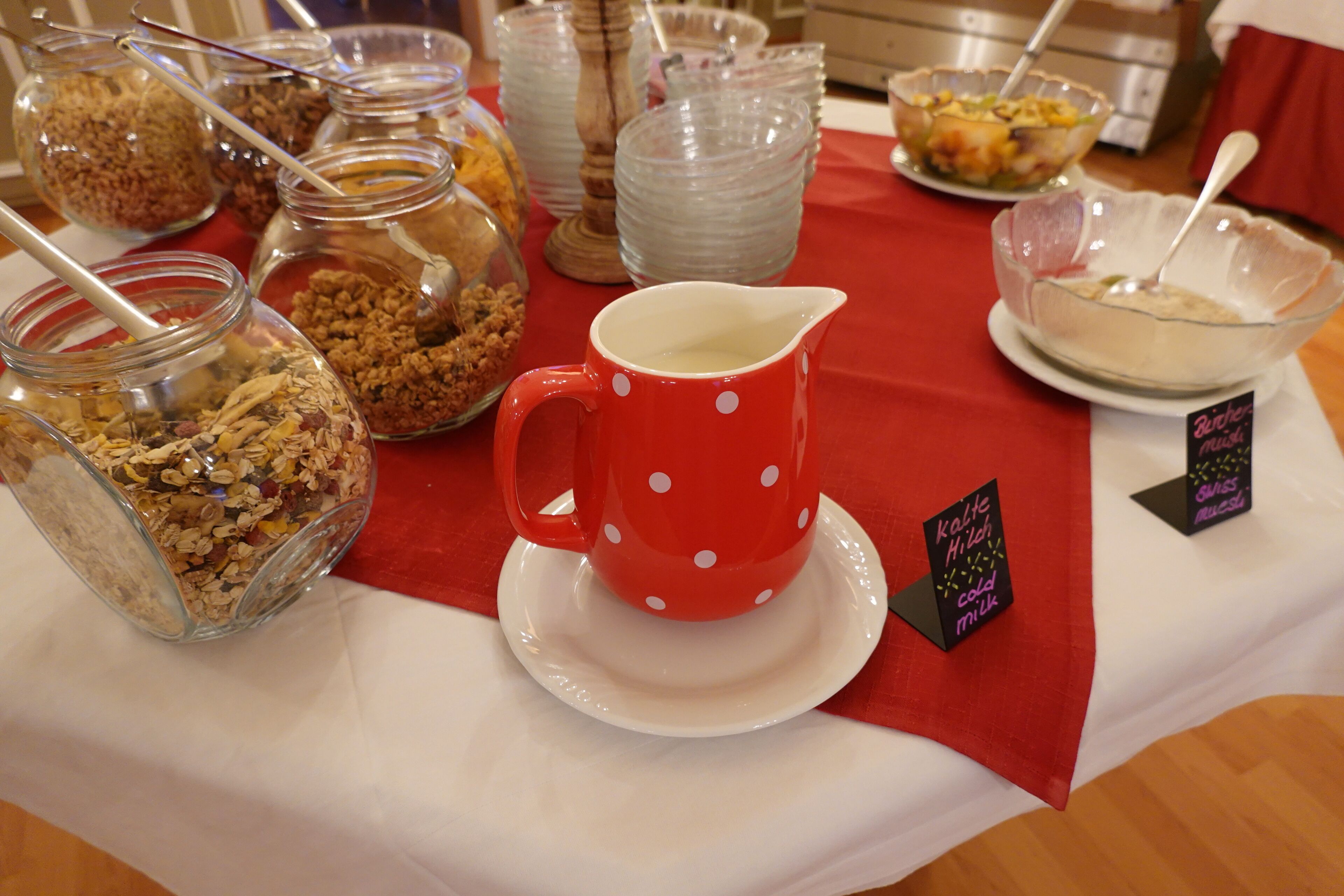 A table with various food items and a red polka-dotted mug.