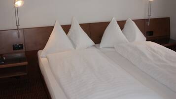 A hotel room with a neatly made bed, two bedside tables, a headboard, and a framed artwork on the wall.