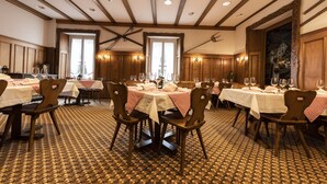 A dining area with multiple tables set for guests, wooden chairs, and a patterned carpet. - Hotel Schweizerhof Engelberg (Engelberg)