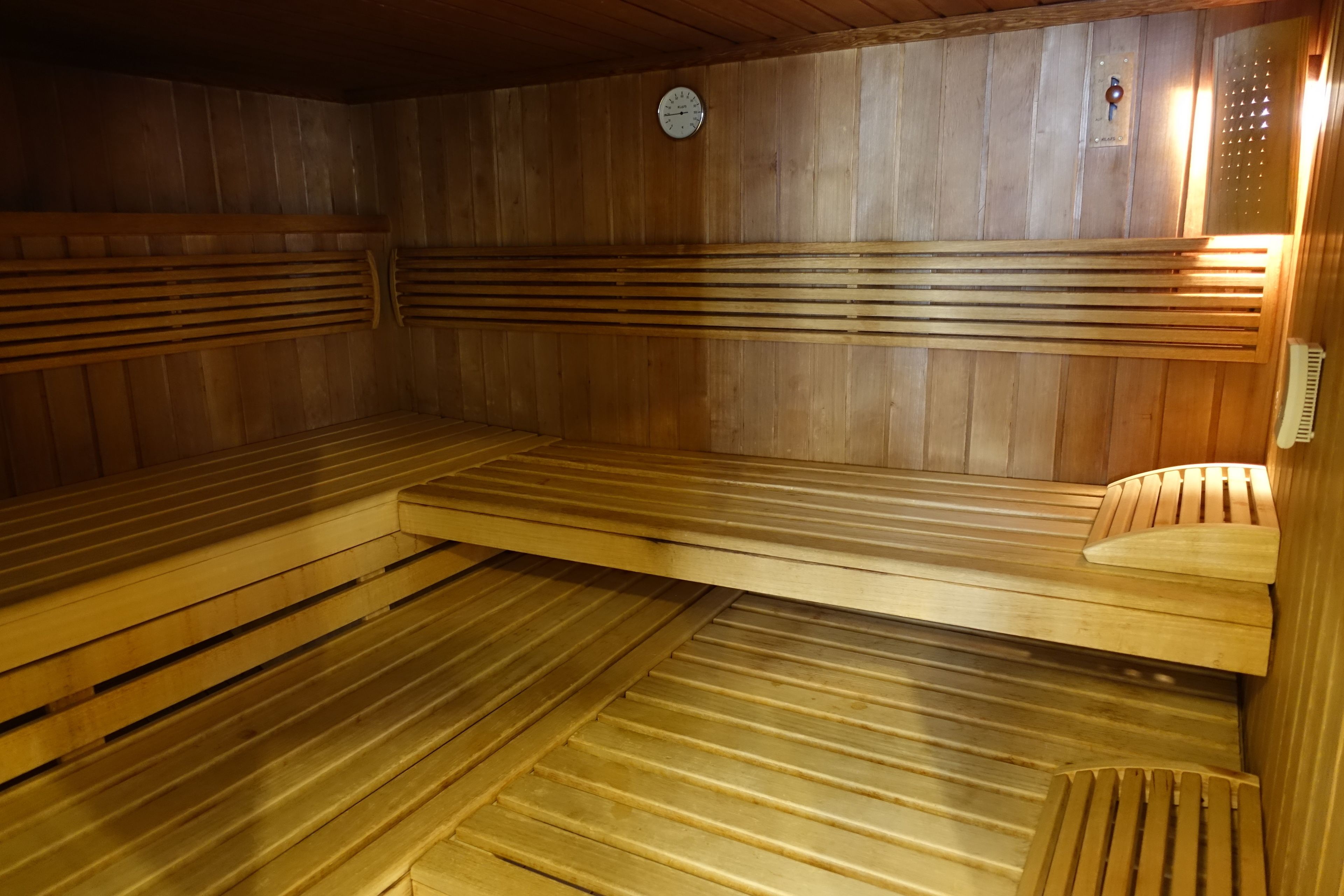 Eine Sauna mit Holzbänken und einer Uhr an der Wand.